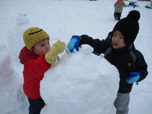 雪だるまに触れる2歳児
