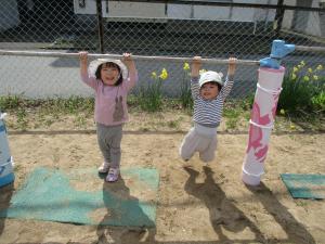 友達と一緒に鉄棒にぶら下がる２歳児