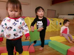 プレイルームで大型積み木で何をしようかと考える１歳児