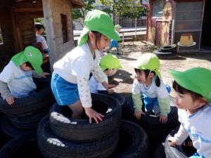 園庭でタイヤ遊びをする4歳児