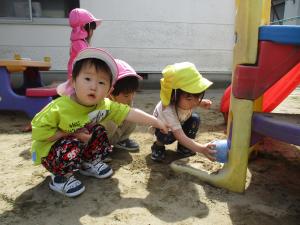 砂遊びのお椀で虫を捕まえようとする2歳児うさぎ組