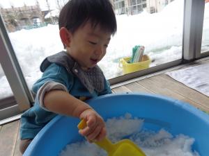 タライに入った雪を笑顔で触る０歳児