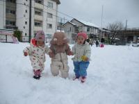 ３人で手をつなぎ雪の上を歩く１歳児