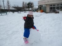 大きな雪玉の上に座る２歳児