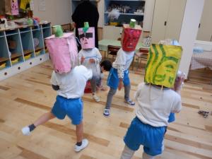 作ったお面をかぶり豆をまき合う4歳児