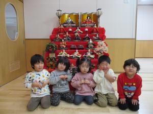 お雛様の前でポーズをとる2歳児