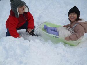 そり遊びをする２歳児二人